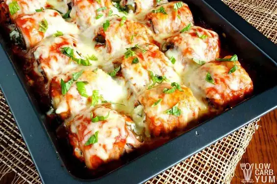 Delicious stuffed eggplant rolls with ground meat, wrapped in bacon, and topped with tomatoes and cheese. A perfect dish to feed a crowd! | LowCarbYum.com